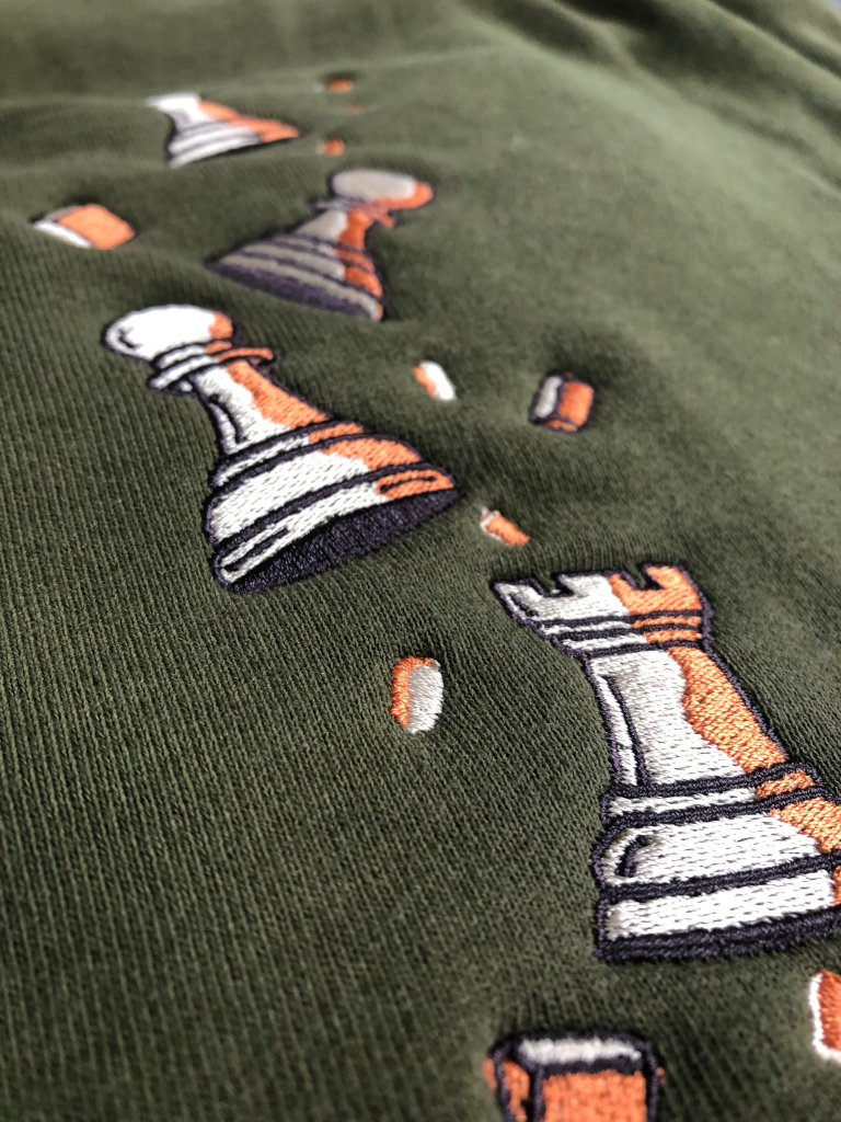 Olive Pawn Chip Sweatpants by Smothered Mate - closeup view of embroidery